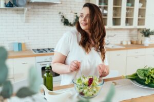Woman in kitchen eating a healthy salad to support vein health in Portland, OR