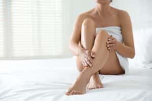 Woman's legs sitting on bed after sclerotherapy for veins in Portland, OR
