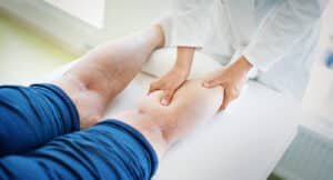 Vein specialist examines a patient’s leg with visible varicose veins during an in-office evaluation.